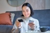 Woman smiling while looking at her credit card in one hand while holding her phone in the other hand 