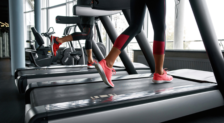 Man and woman running on treadmill at gym