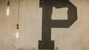 Letter P painted on a white wall next to two light bulbs