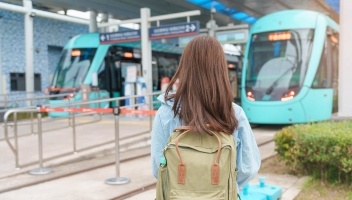 Woman traveler facing away from camera while waiting on subway train