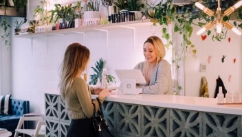 A woman paying for something at a chic and trendy cafe.