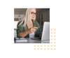 Woman with long hair and glasses holding her credit card while typing on a laptop
