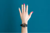 Hand with black watch and multicolored nail polish