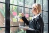 Woman in UX design is card sorting using sticky notes on a window