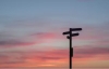 A signpost in silhouette against a sunset-pink sky