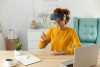 Woman in yellow shirt pointing while wearing a VR headset