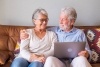 Cheerful senior couple using laptop while sitting on sofa