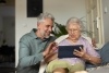 Mature man helping his senior mother use a tablet