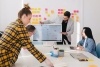 An internal team meeting in a white room with lots of sticky notes on a whiteboard.