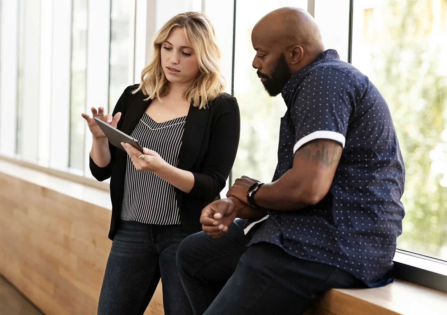 Image of man and woman in a hallway talking and looking at a tablet in the workplace