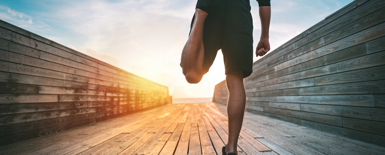 Photo of person stretching their legs on a bridge during a sunrise