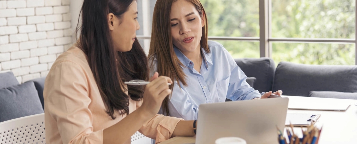 Photo to two professionals sitting in front of a laptop while having a discussion