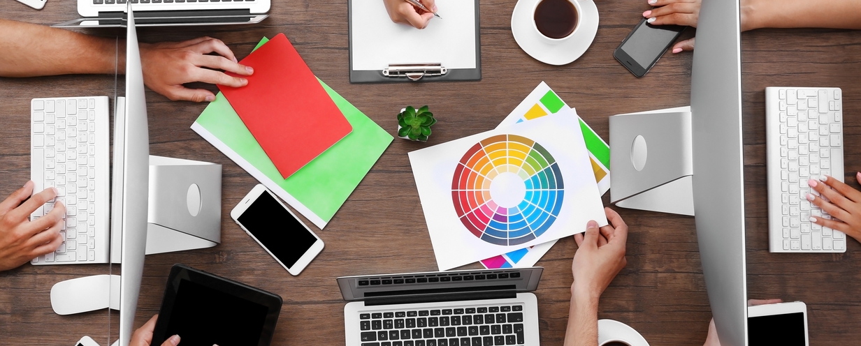 Photo of a group of designers huddled around a conference table looking at a color wheel