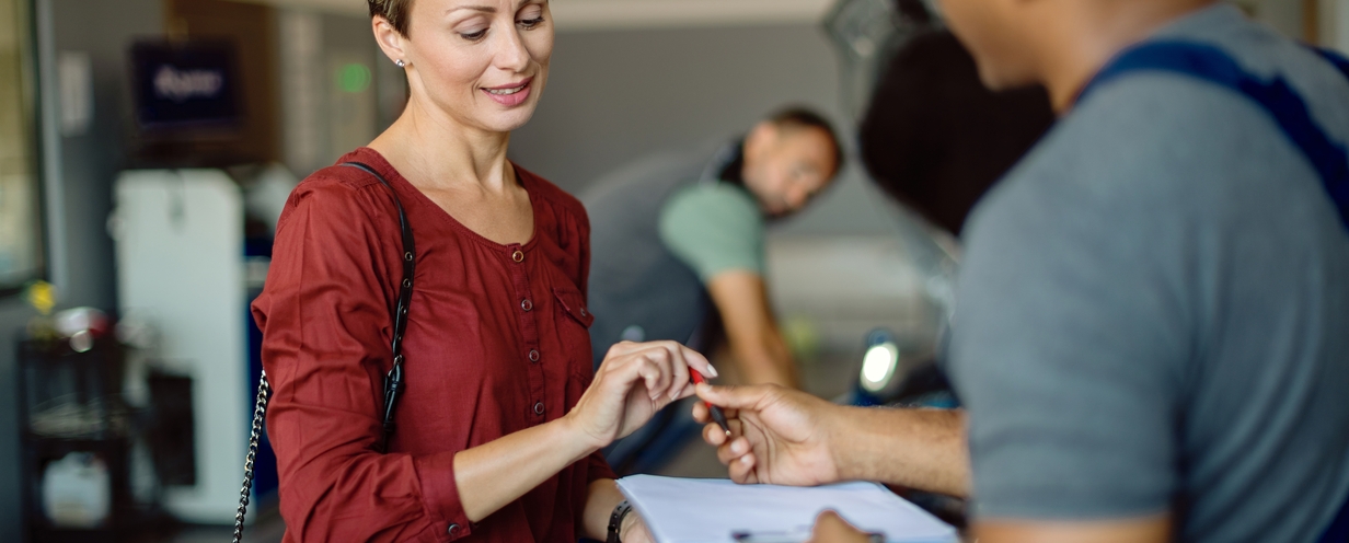 mid-adult-woman-signing-documents-at-car-workshop