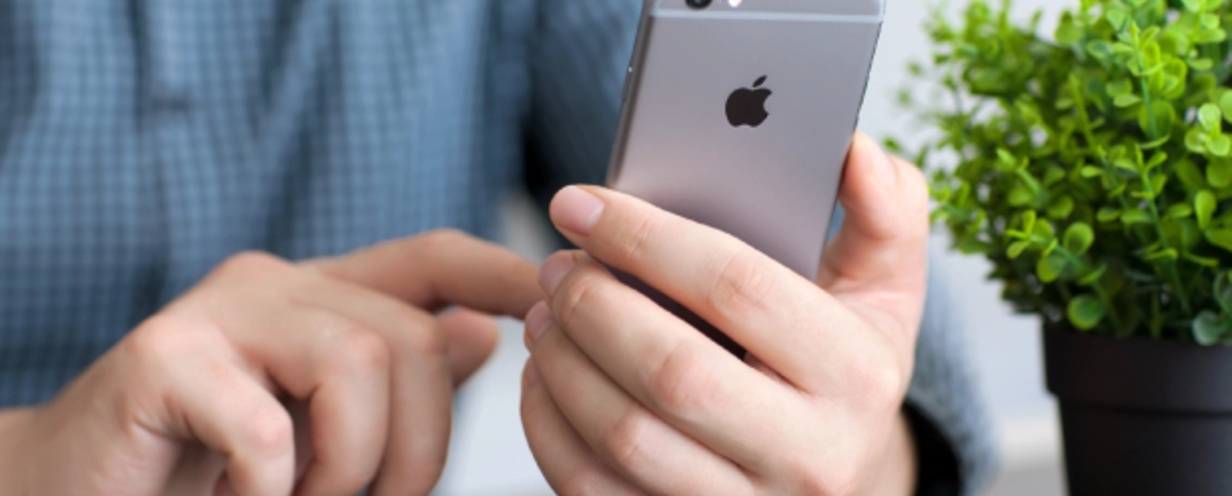 Photo of a businessperson's hands holding and tapping on their iPhone