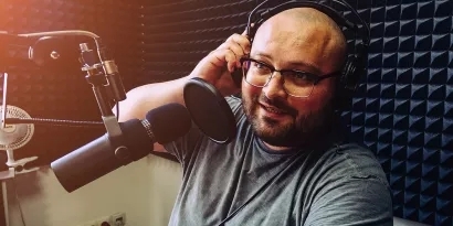 Photo of a man in a recording studio speaking into a microphone