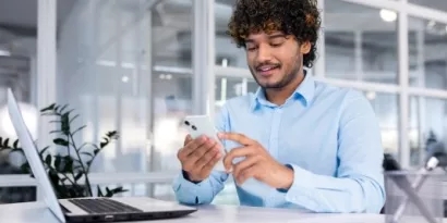 Business professional using their phone while in front of their laptop