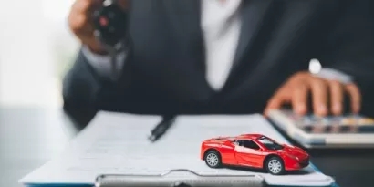 Red toy car on a desk with a person out of focus in background
