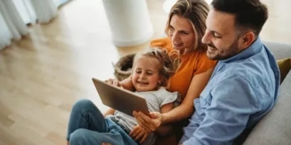 Family of three sitting together while looking at a tablet