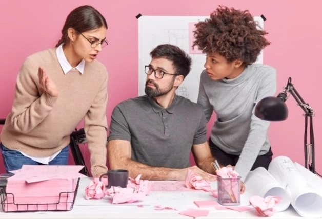 Three people talking to each other in a pink office