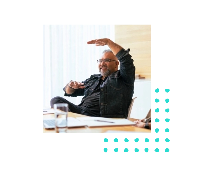 Man wearing glasses, sitting at conference table gesturing with handss
