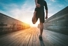 Photo of person stretching their legs on a bridge during a sunrise
