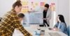 Photo of 4 business professionals reviewing a presentation on a computer monitor