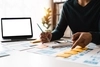 Image of a person sitting at a table reviewing documents with a pencil in hand 
