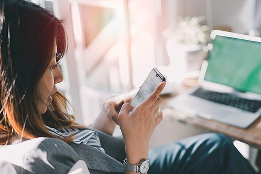 Woman sitting at desk looking at mobile phone