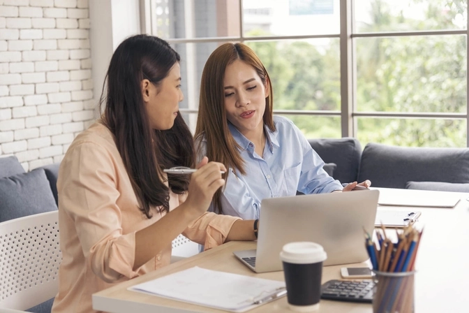 Photo to two professionals sitting in front of a laptop while having a discussion