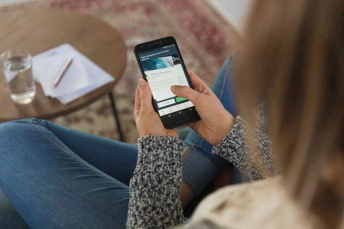 Photo of a woman sitting on a couch looking at a mobile phone
