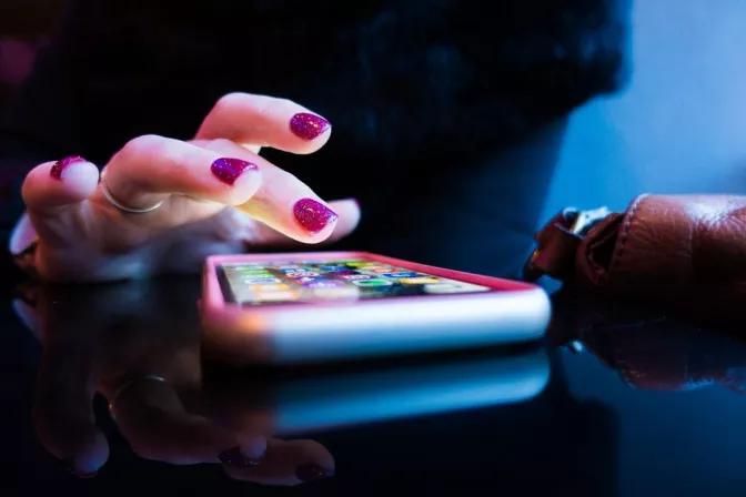Woman's hand tapping on an illuminated mobile phone