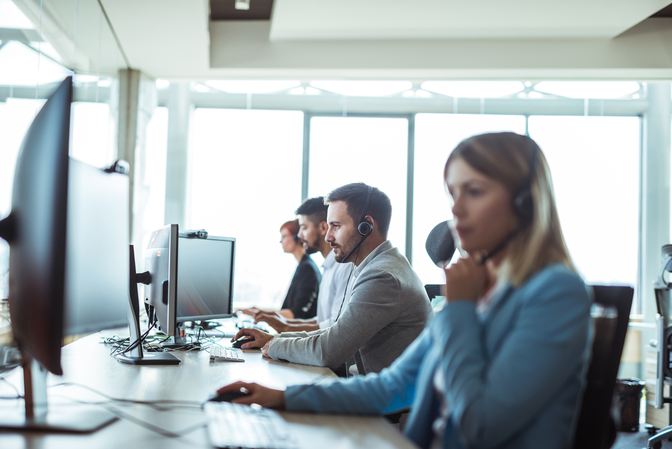 Photo of 4 call center workers answering customer support calls