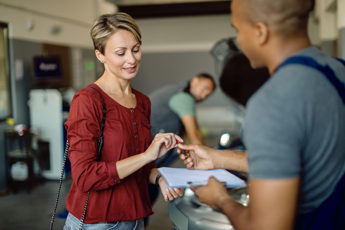 mid-adult-woman-signing-documents-at-car-workshop