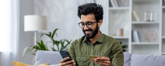BLOG-Male-using-banking-app-on-sofa-happy-and-smiling