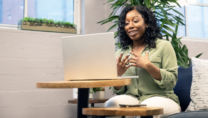 Image of a woman sitting in front of a laptop speaking and gesturing with her hands